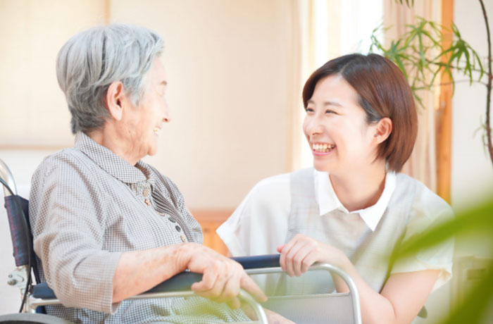 お年寄りの女性と笑顔で会話する歯科スタッフのイメージ